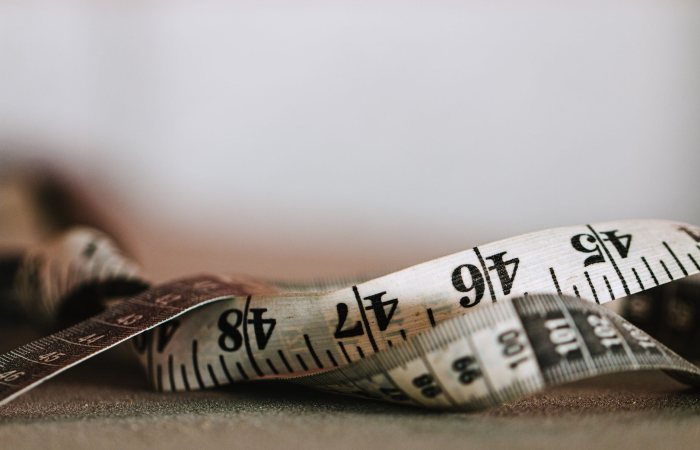 Extreme close-up shot of a coiled measuring tape showing numbers in inches and centimeters.