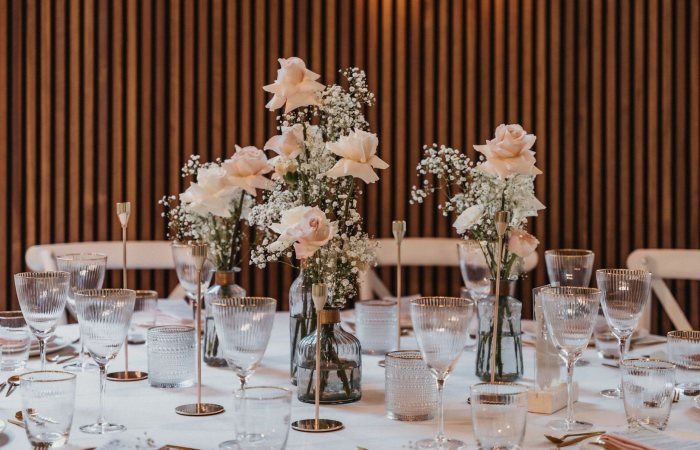Stylish table setup featuring pink roses and elegant glassware, perfect for weddings or special events.