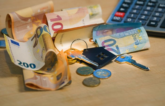 Euro banknotes and coins with house keys on a table symbolize finance and real estate.
