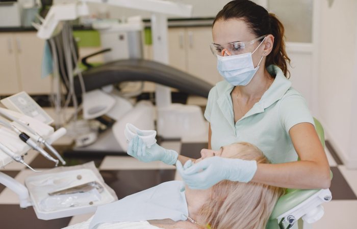 Female dentist with face mask examines patient in modern clinic. Healthcare setting.