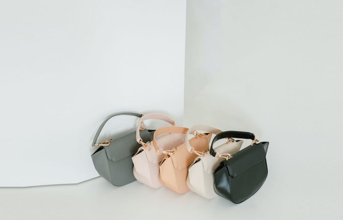 A stylish assortment of pastel handbags elegantly displayed against a minimalist backdrop in a studio setting.