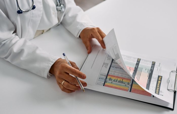A medical professional checking patient reports with a clipboard in an office setting.