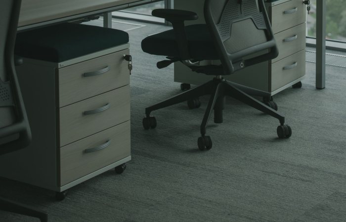 A sleek office setup featuring ergonomic chairs and drawer units in a well-lit space.
