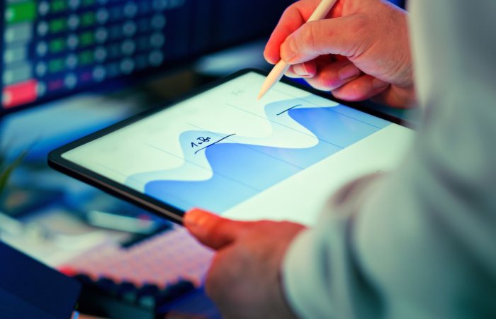 Professional analyzing data chart on a tablet with stylus in an office setting.