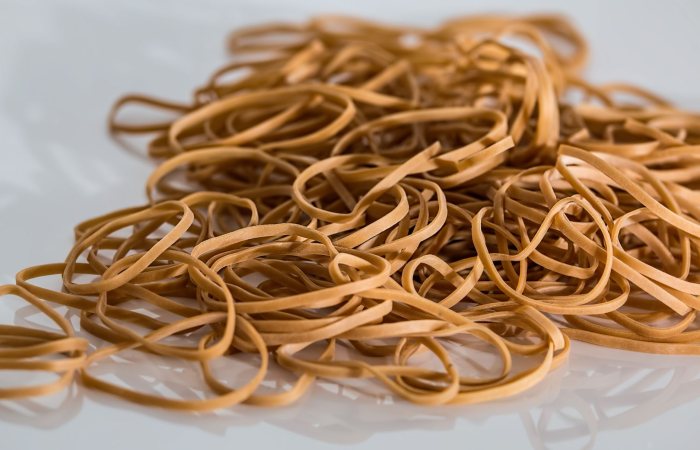 A close-up image of a scattered pile of brown rubber bands on a reflective surface.