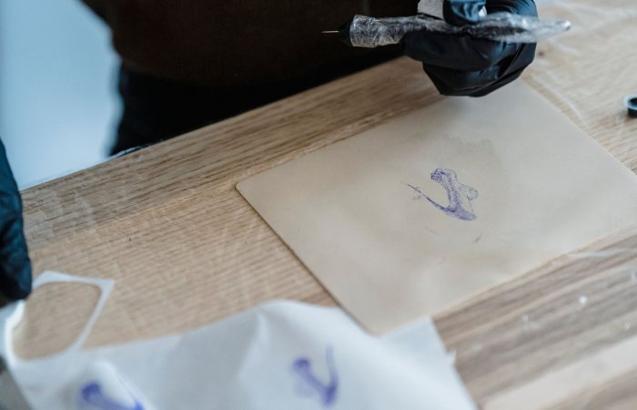Tattoo artist in gloves preparing a design on transfer paper, ready for stencil application.