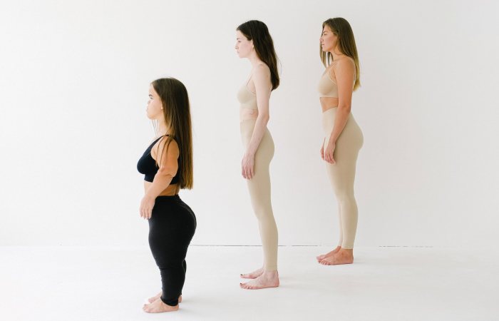 Three women of varying heights and body types in activewear promoting body positivity and diversity.